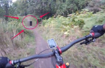 ciclista se encuentra con un oso negro en el medio del camino y de la sorpresa cae de bruces hacia unos arbustos sendero alaska Kincaid park cyclist faces bear road