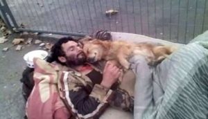 Captan a un hombre sin hogar y su perro abrazados fuertemente para consolarse en el desamparo